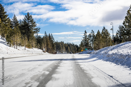 Driving on an ice and snow covered road through the Sierra mountains on a sunny day, Nevada