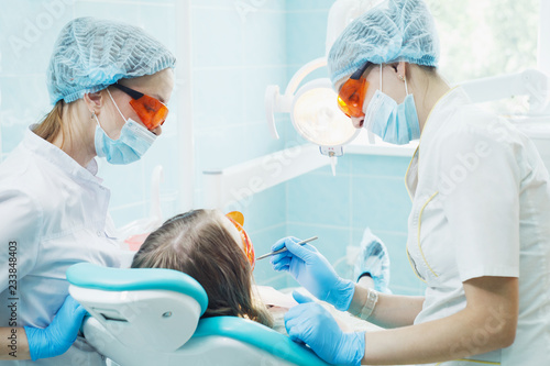 Girl patient with dentist and assistant in a dental treatment