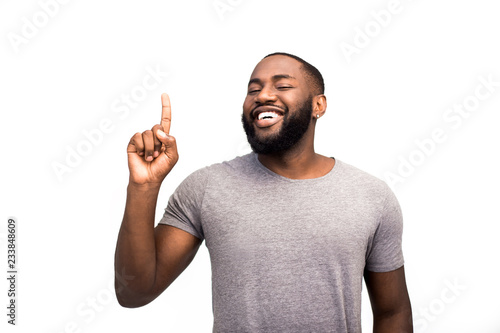 Billede på lærred A confident black man, a successful African American, a happy knowledgeable expert in his field, an advertising sales assistant consultant, advises users to look upward with a finger over his head