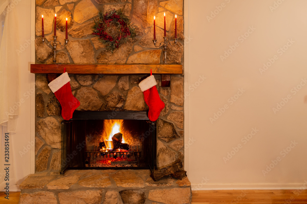 Warm fireplace with wreath, candelabras and two Christmas stockings in the family home.
