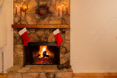 Warm fireplace with wreath, candelabras and two Christmas stockings in the family home.