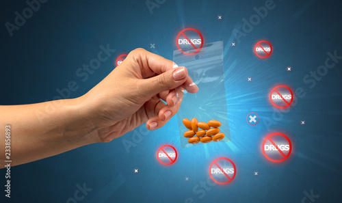 Hand giving pills with anti-drug concept and not allowed signs around photo