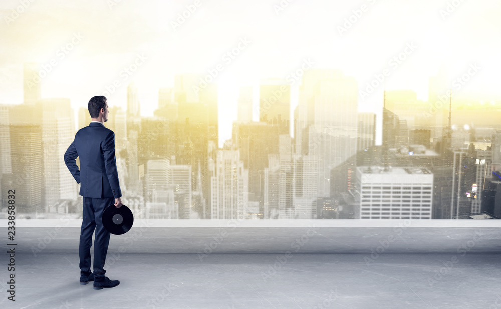 Businessman standing with his back on a roof with objects in his hand
