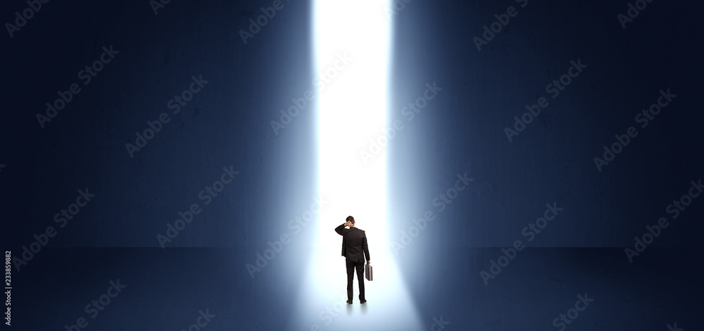 Businessman standing and seeing the light at the end of a big wall
Businessman standing and seeing the light at the end of a big wall