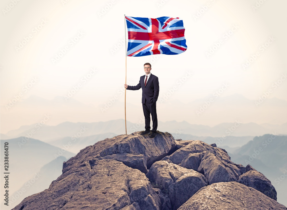 Successful businessman on the top of a mountain holding victory flag
