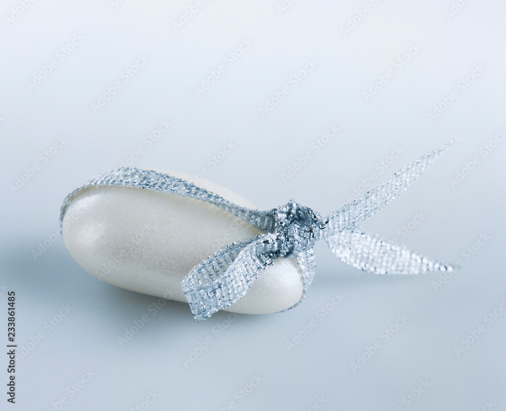 Fototapeta premium White candy-coated almond tied with a silver ribbon