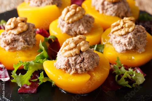 Ripe peaches stuffed with tuna mousse and decorated with walnuts close-up. horizontal
