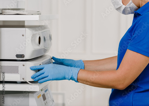 Female doctor in uniform using ultrasonic machine in hospital
