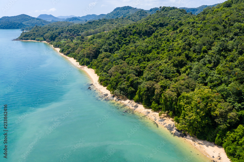 Aerial drone view of an empty tropical sandy beacj surrounded by lush green forest Aerial drone view of an empty tropical sandy beacj surrounded by lush green forest