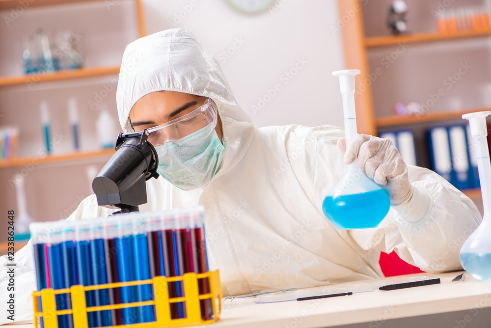 Young biochemist wearing protective suit working in the lab Young biochemist wearing protective suit working in the lab