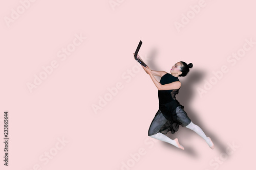 Asian ballerina holding a laptop on studio