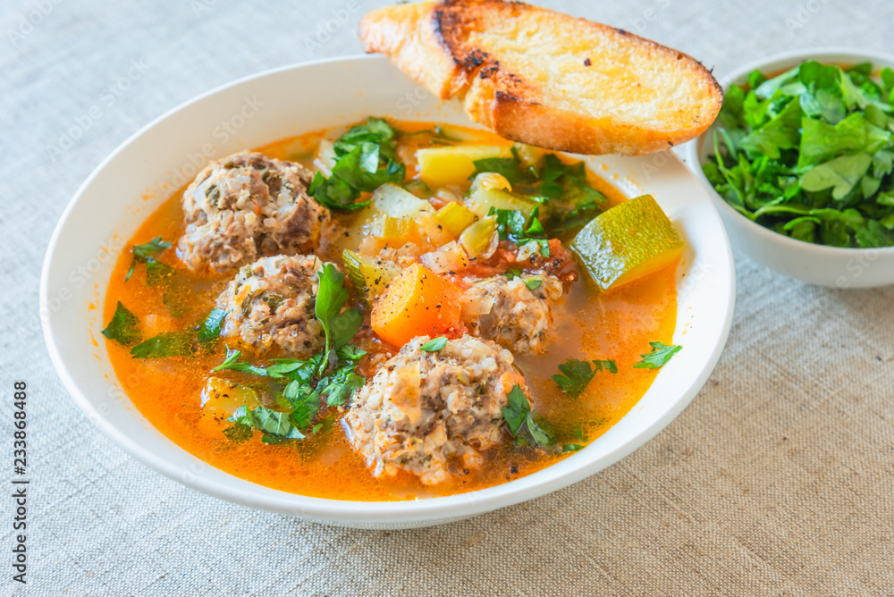 Mexican soup with meatballs and vegetables in a plate on a rustic background - Albondigas