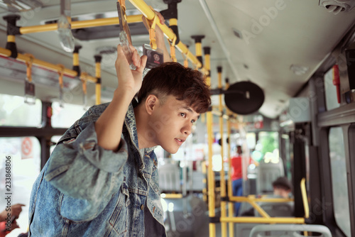 People, lifestyle, travel and public transport. Asian man standing inside city bus.
