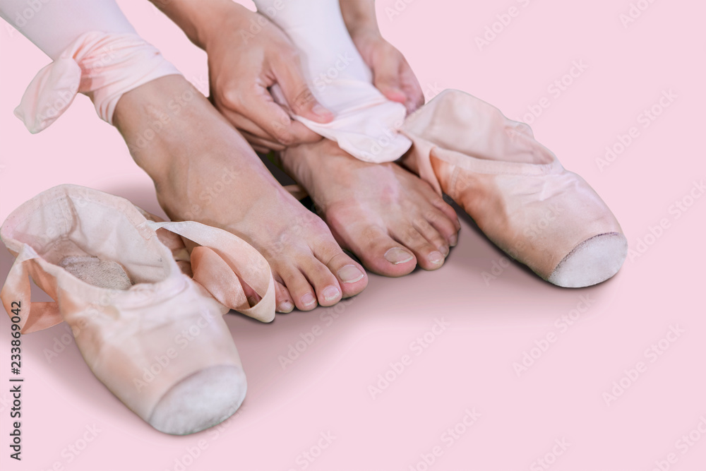 Female dancer taking off ballet shoes on studio