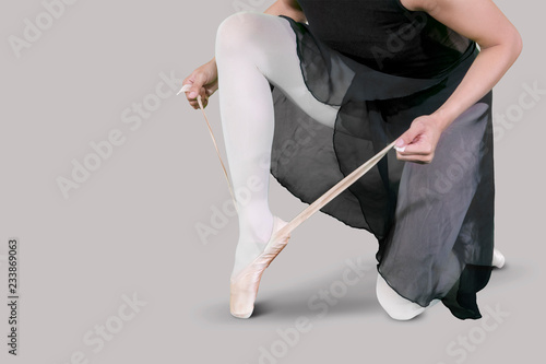 Female dancer ties up her ballet shoes