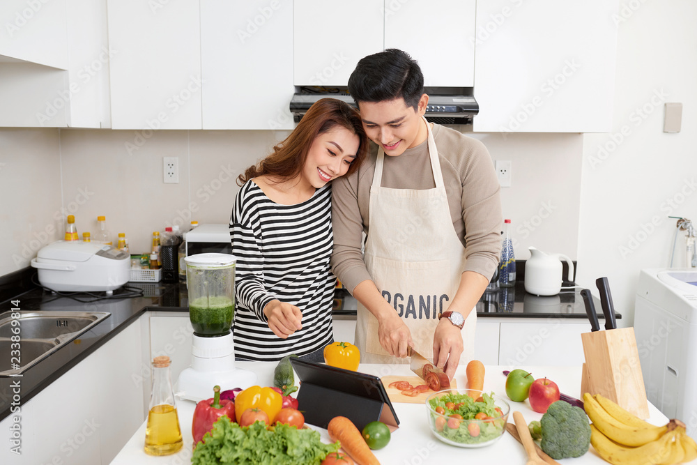 Happy young couple have fun in modern kitchen indoor while preparing vegetables food for lunch Happy young couple have fun in modern kitchen indoor while preparing vegetables food for lunch