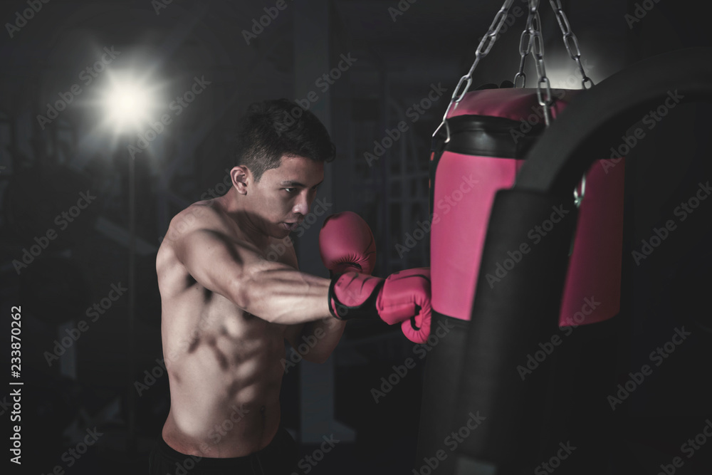 Male boxer hitting a punching bag at gym