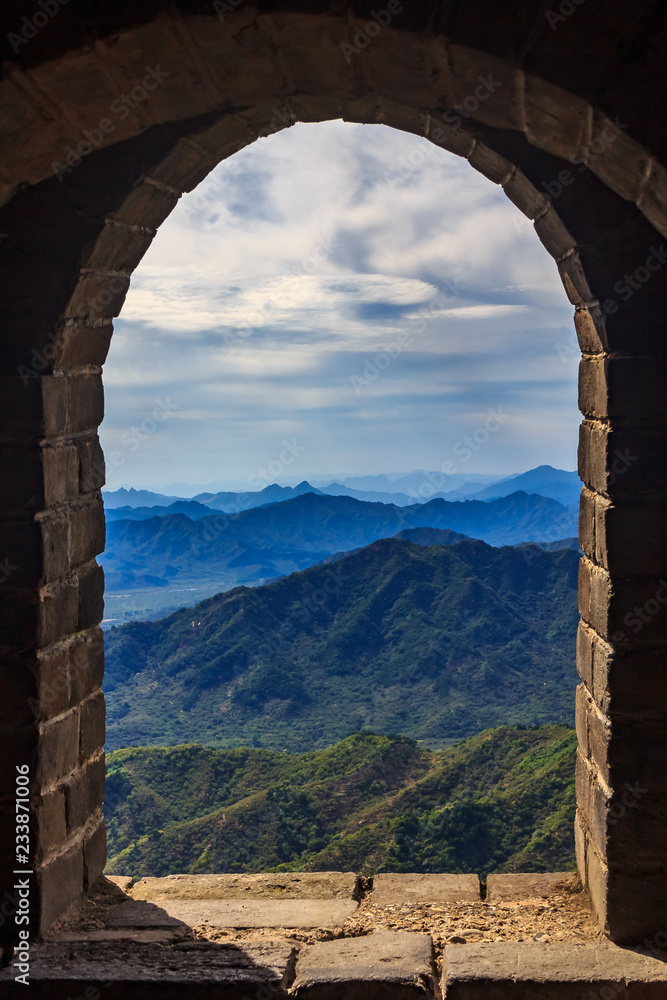 View onto a mountain range through a window in a watchtower of the Great Wall of China in the Mutianyu village, near Beijing