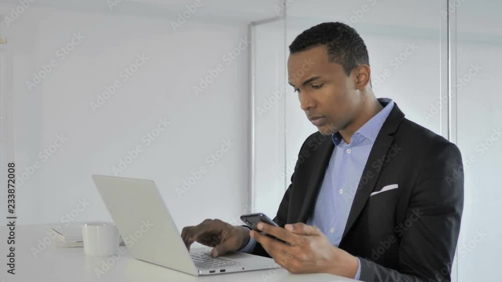 Frustrated Casual Afro-American Businessman Reacting to Loss while Using Smartphone Frustrated Casual Afro-American Businessman Reacting to Loss while Using Smartphone