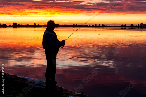 Fisherman fly fishing during sunset on the banks of lake Zoetermeerse Plas, Zoetermeer, Netherlands