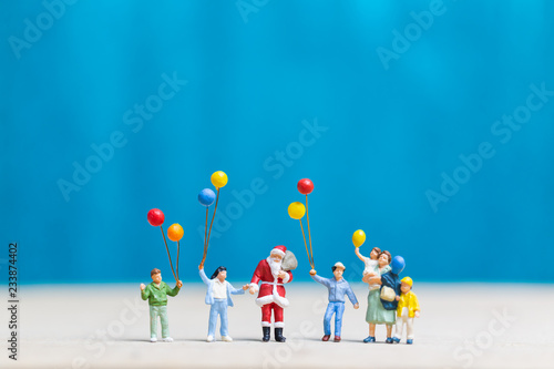 Miniature people: Santa Claus and children holding balloon