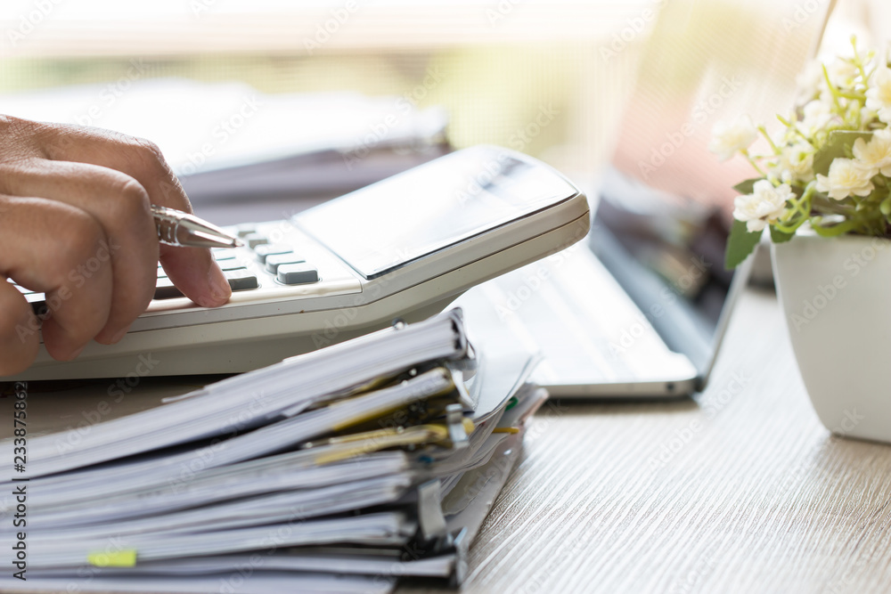Accountant hand use calculate financial report, counting on calculator for checking financials analyzing documents paperwork with laptop computer in modern office, Accounting planning budget concept Accountant hand use calculate financial report, counting on calculator for checking financials analyzing documents paperwork with laptop computer in modern office, Accounting planning budget concept