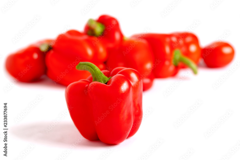 One sweet pepper, red, on a blurred background of vegetables, light on the right. One sweet pepper, red, on a blurred background of vegetables, light on the right.