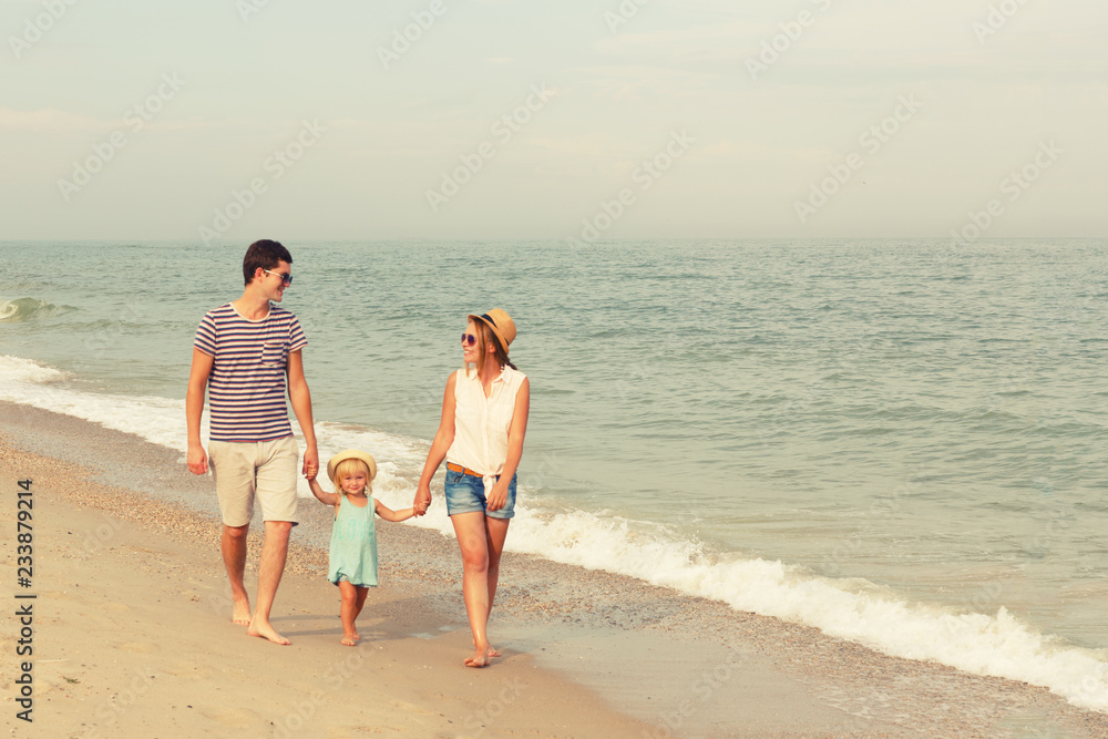 Happy family! Dad, mother and daughter are walking along the sea. Copy space.