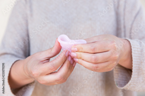 The menstrual cup is holding by woman hands. Selective focus.