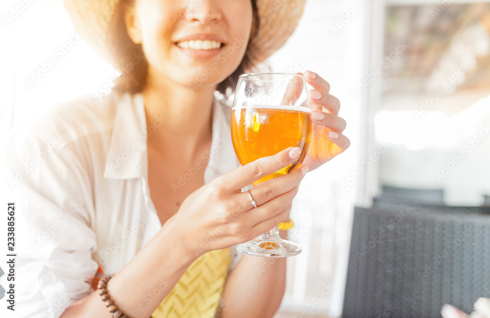 close up of smiling woman holding glass of light beer close up of smiling woman holding glass of light beer