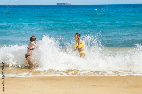 Young woman tourist in swimsuit having fun in wavy waters of Mediterranean sea, storm weather at the sea concept