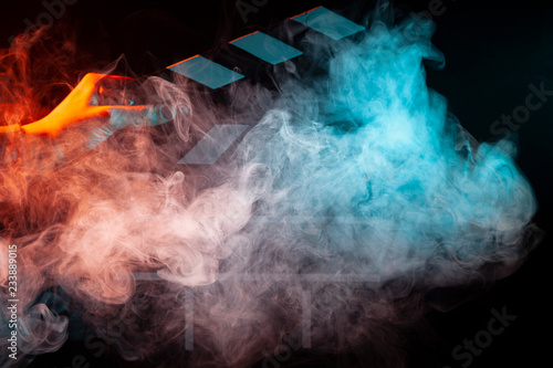 Black and white clapperboard for cinema close up among multicolored red and green smoke in a man’s hand giving a command to start shooting on a black isolated background
