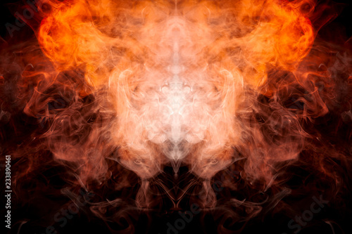 A background of orange and yellow wavy smoke in the shape of a ghost's head or a man of mystical appearance on a black isolated ground. Bright abstract pattern of steam from vape.