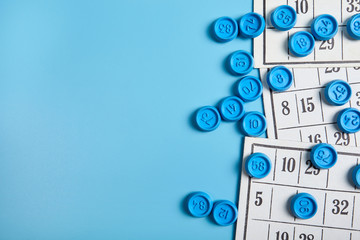 Bingo balls and cards on blue background with copy space.