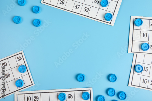 Bingo balls and cards on blue background with copy space.
