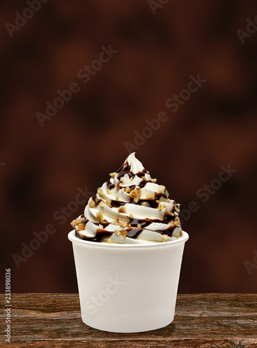 Soft vanilla ice cream with Chocolate sauce and hazelnut / filbert sundae or frozen custard isolated on brown background photo