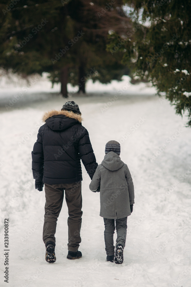 Happy father with his son walks through the park in the snowy winter weather