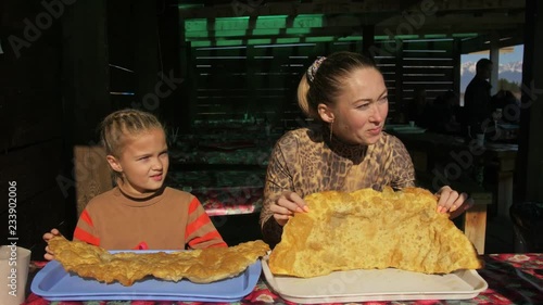 Woman and children eating national Buryat Mongolian dish cheburek. Big large xxxl 68cm heburek fry with cheese meat onions into cooking pot in oil. Fried piadina naan pita tortilla shelpek cheburek. photo