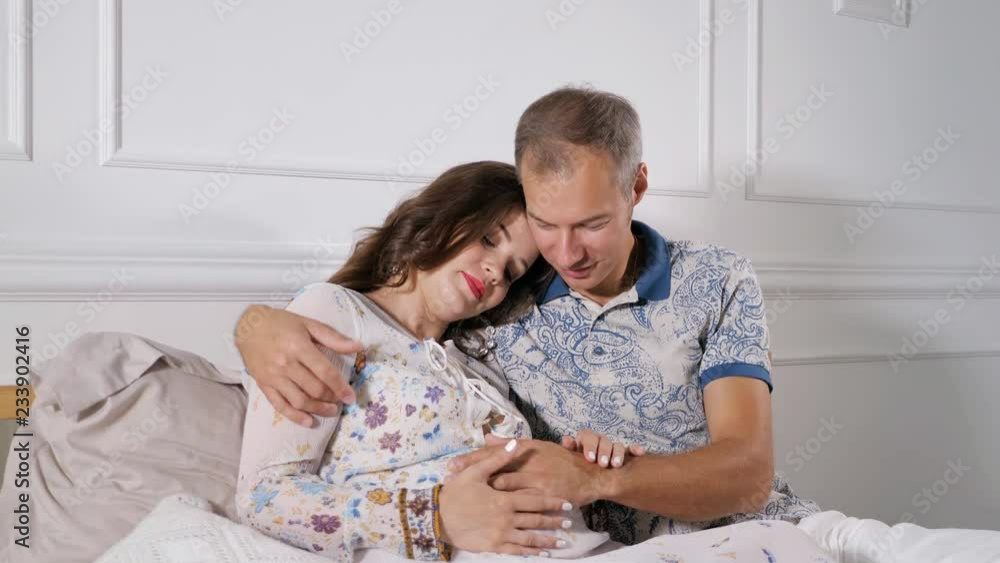 pregnant woman and man hugging sitting in bed. pregnant woman and man hugging sitting in bed.