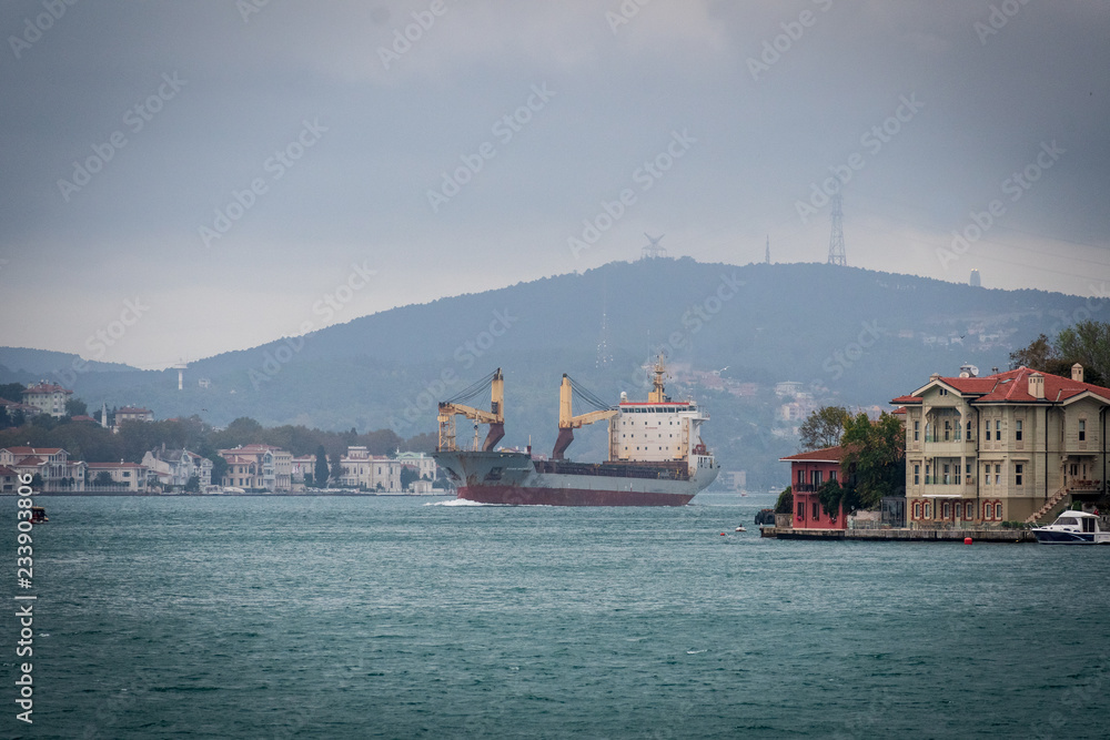 Ship going through the Bosporus Strait with hill at the backfround and luxury house at the foreground
