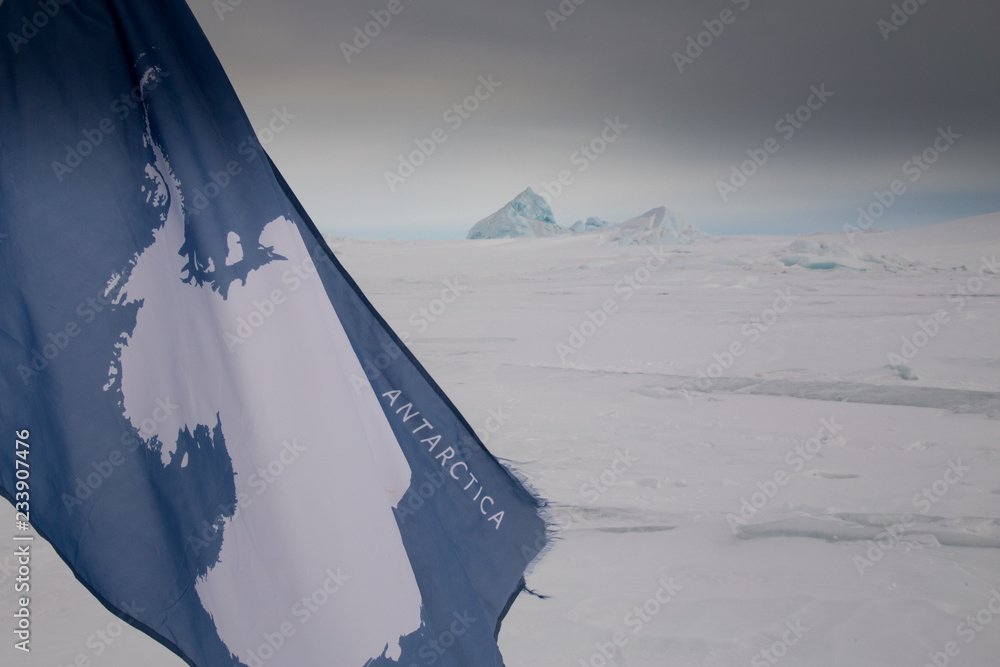 A flag with the image of the continent of Antarctica on the sea ice of the weddell sea in antartica