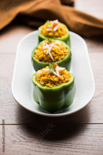 Stuffed capsicum or bharwa shimla mirchi is a popular Indian main course recipe. Served in a plate over moody background. Selective focus