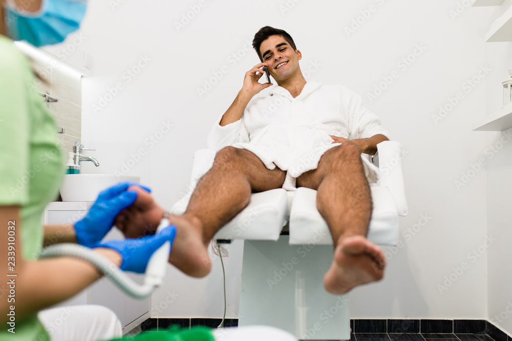 Obraz premium Young man having pedicure treatment in a modern beauty salon.