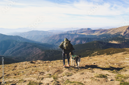 The girl travels from Husky. Ukrainian Carpathian Mountains. Top of the mountain. Woman in sweater with ornament. Black and white dog
