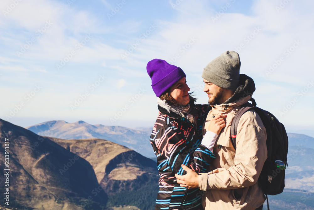 Beautiful couple in the mountains. Autumn. View from the mountain. Necking. Tourists in the hike