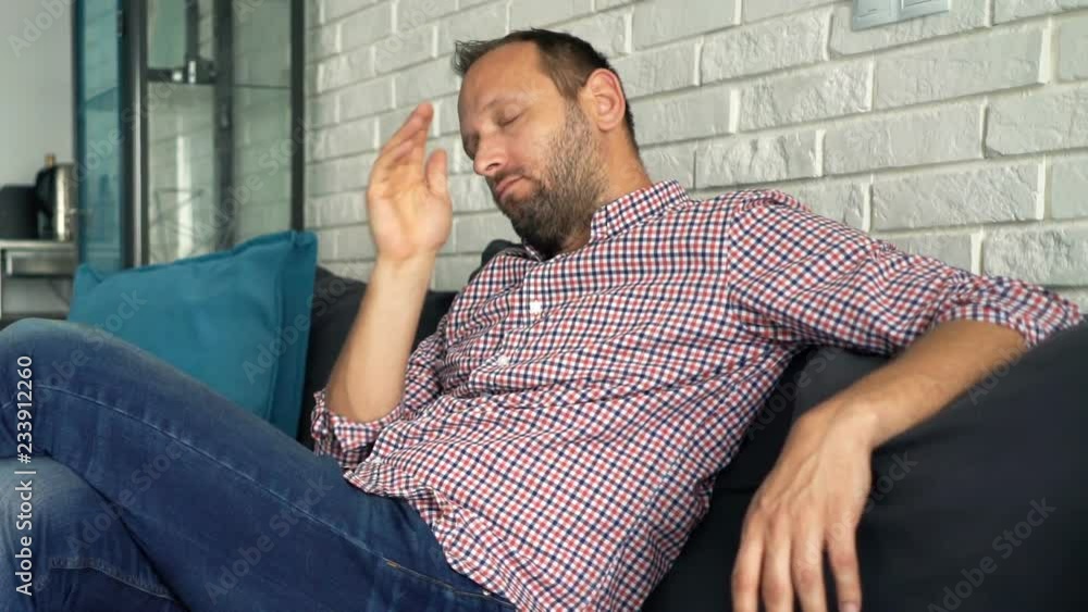Sleepy, tired man sitting on sofa at home Sleepy, tired man sitting on sofa at home