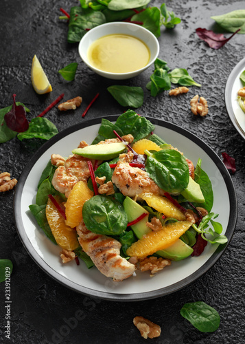 Grilled chicken with orange and avocado salad on rustic background