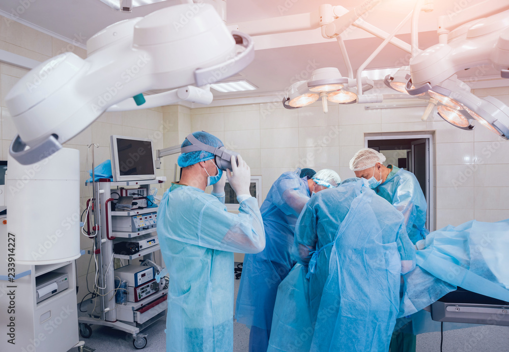 Doctor in a surgical room with virtual reality glasses on the background of the real operation. Doctor in a surgical room with virtual reality glasses on the background of the real operation.