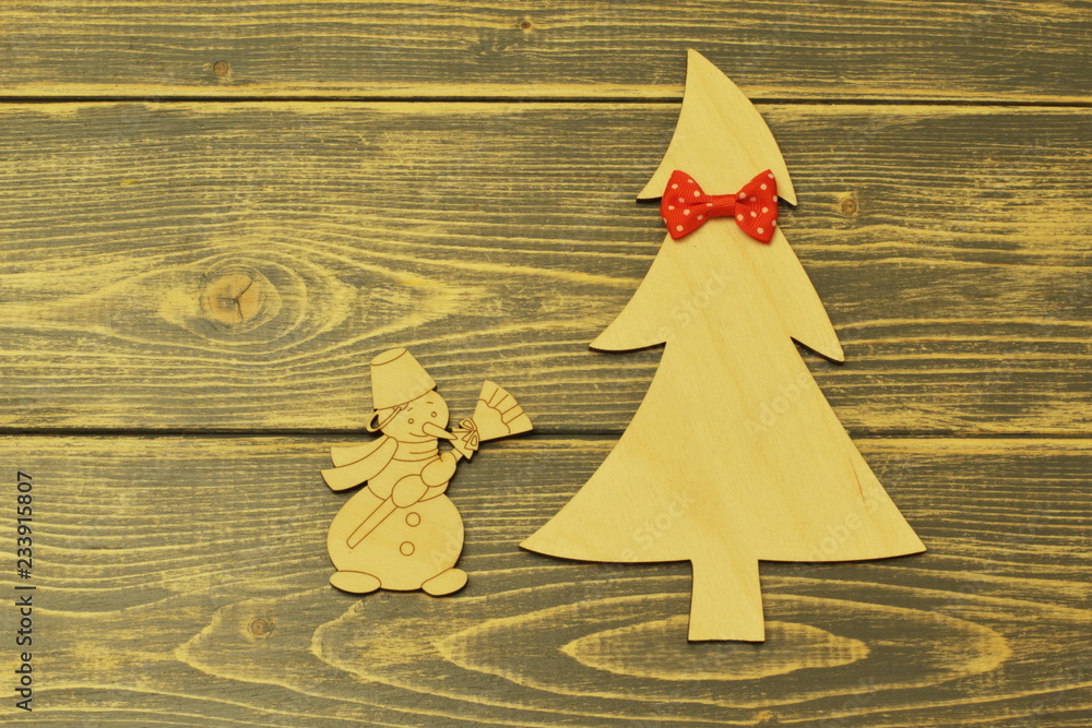 Wooden Christmas tree decorated with red bow tie and cheerful vintage snowman with broom on old wooden dark background. Wooden Christmas tree decorated with red bow tie and cheerful vintage snowman with broom on old wooden dark background.
