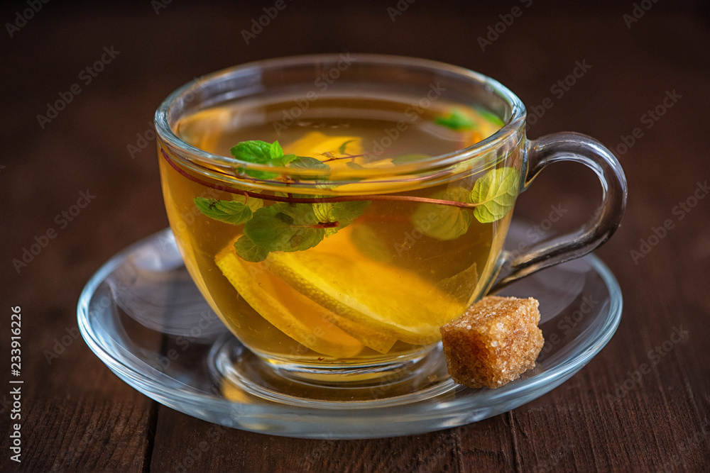 Cup of Lemon tea with lemon slices, cane sugar and mint on dark wooden background